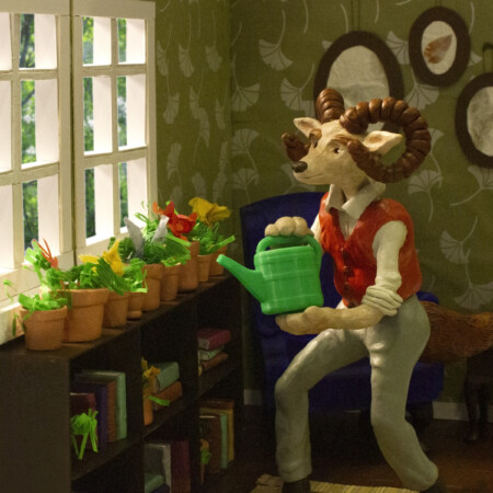 Illustration By Steph Brennan. Sculpture of creature that is a hybrid of a ram and fox. He is in his living room using a green watering can to water his plants.